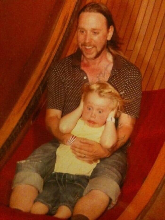 A funny theme park ride picture of a small child on a ride, looking terrified with his hands over his ears.