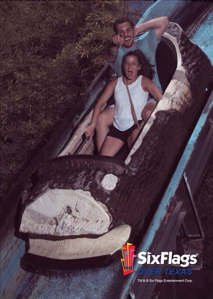 A funny rollercoaster picture of a couple on a log flume, with the woman screaming and the man pointing at the camera.