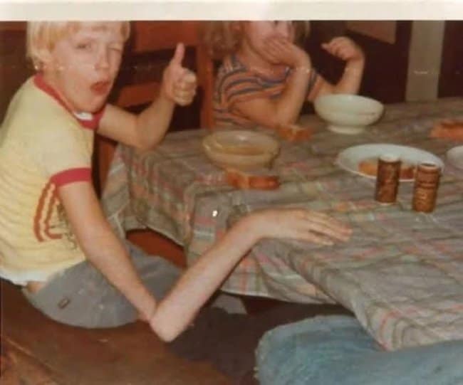 Funny vintage optical illusion photo where a boy giving a thumbs up appears to have an impossibly long, skinny arm.