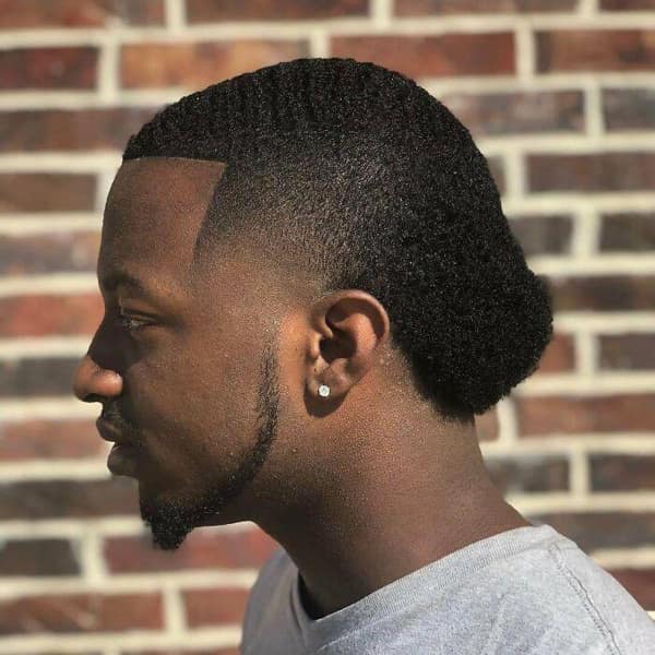 A man with a sharp fade on the sides but a long, wavy mullet in the back.