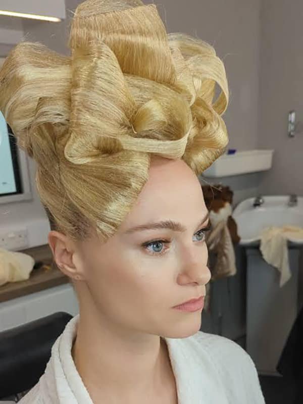 A woman with an elaborate, high-fashion hairstyle featuring a giant bow made of blonde hair.