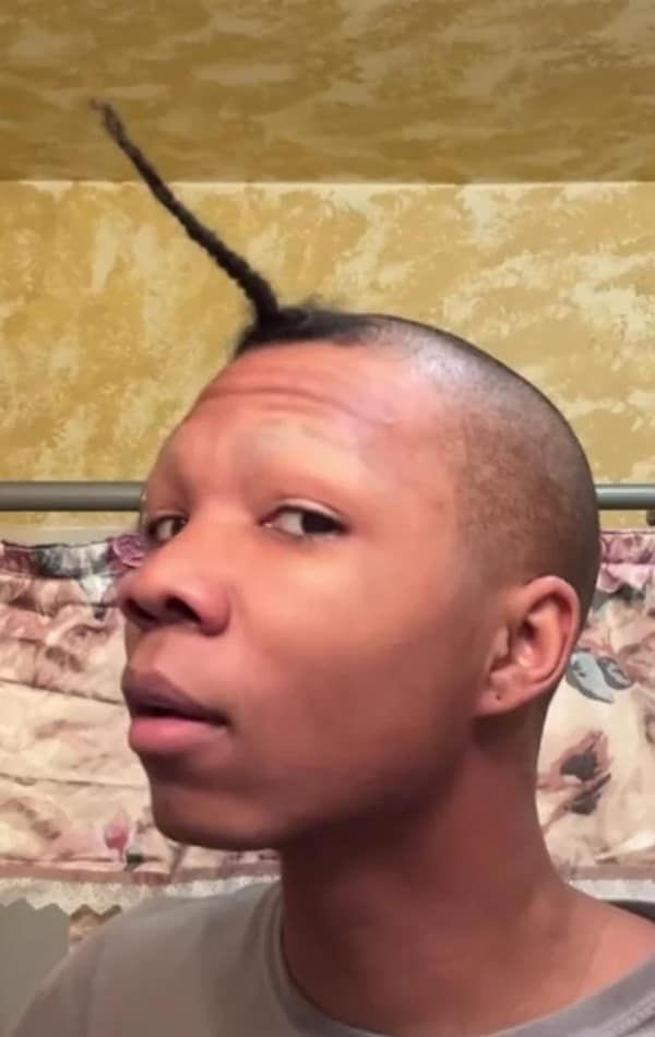 A person with a shaved head, except for a single, long braid sticking straight up from the top.