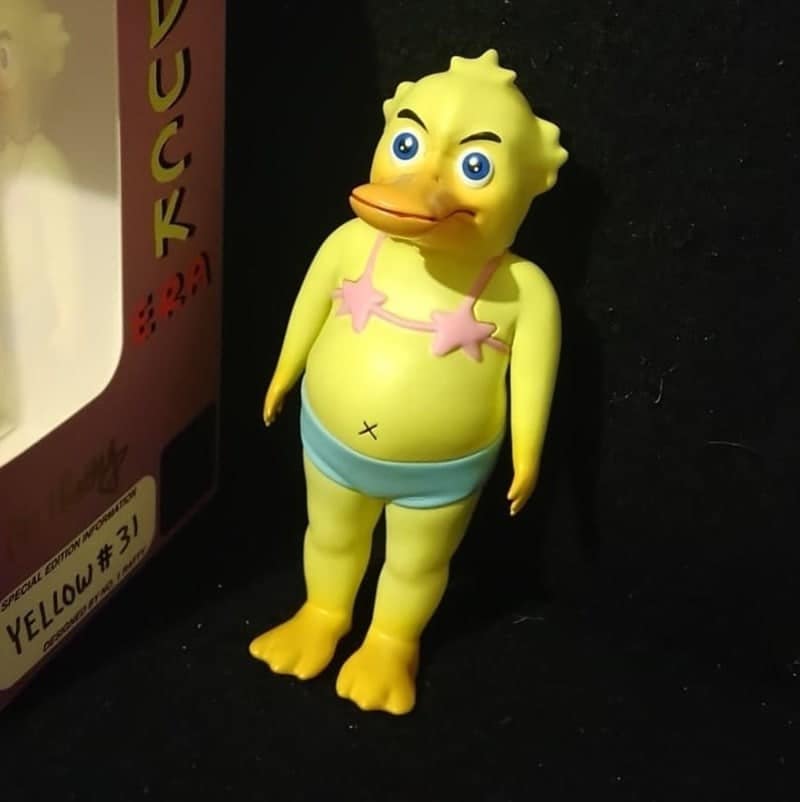 An unhinged toy of a yellow duck with human legs wearing a bikini bottom.