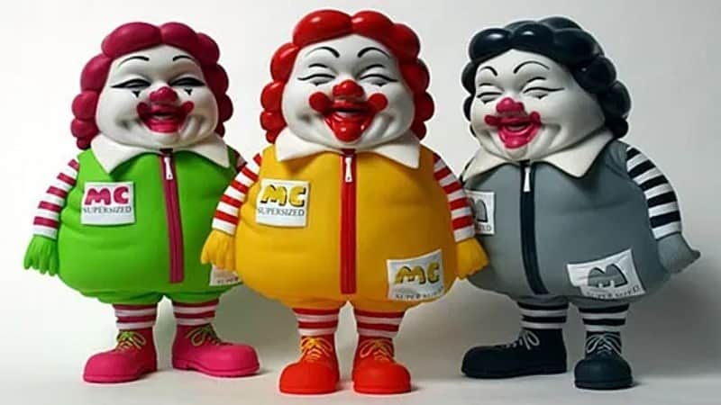 Three vinyl figures of Ronald McDonald looking overweight and sickly.
