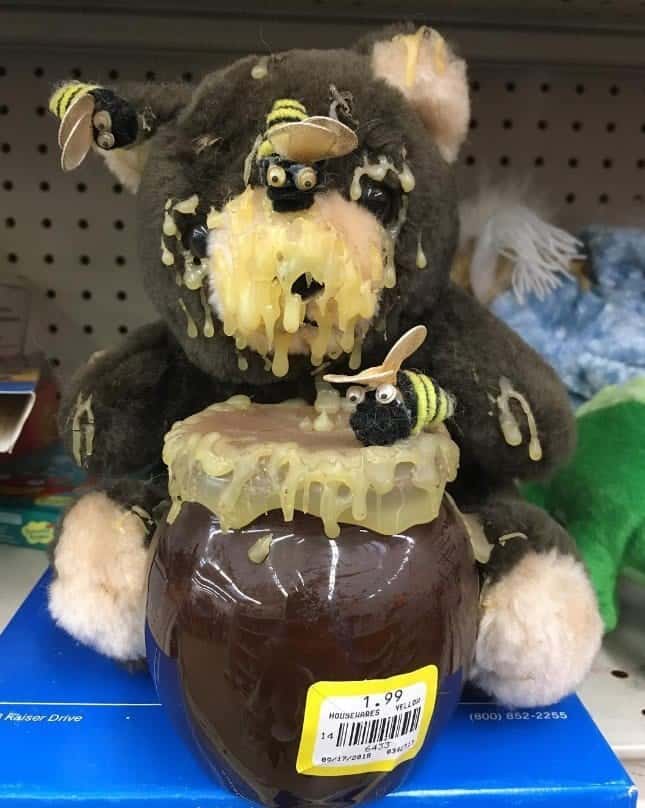 A cursed toy teddy bear covered in melting wax looking like honey with bees on it.