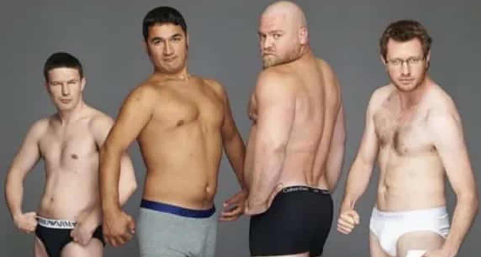A funny group photo of four shirtless men posing in their underwear against a grey background.