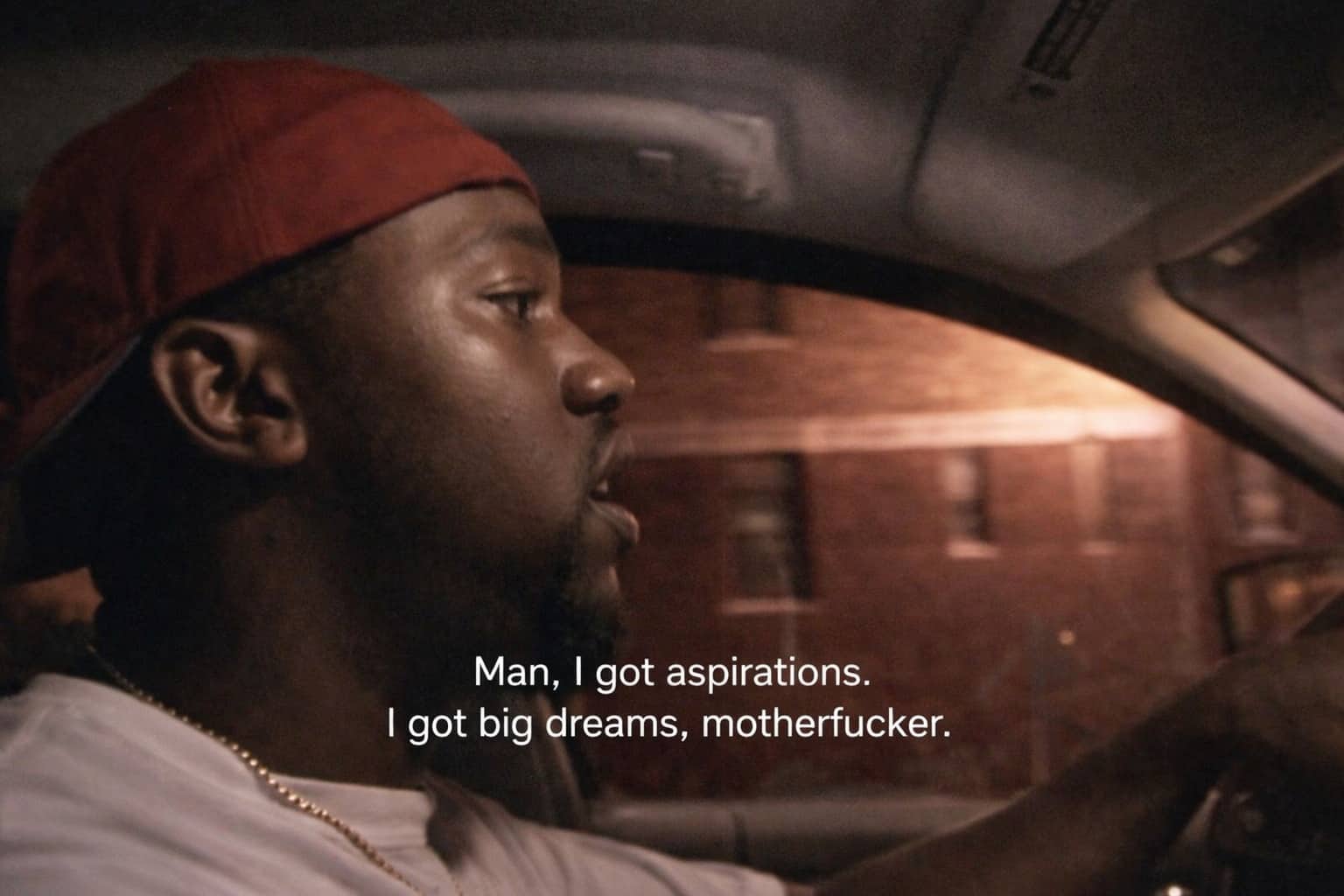 Man in a red hat driving and talking about big dreams and aspirations, confidence memes.