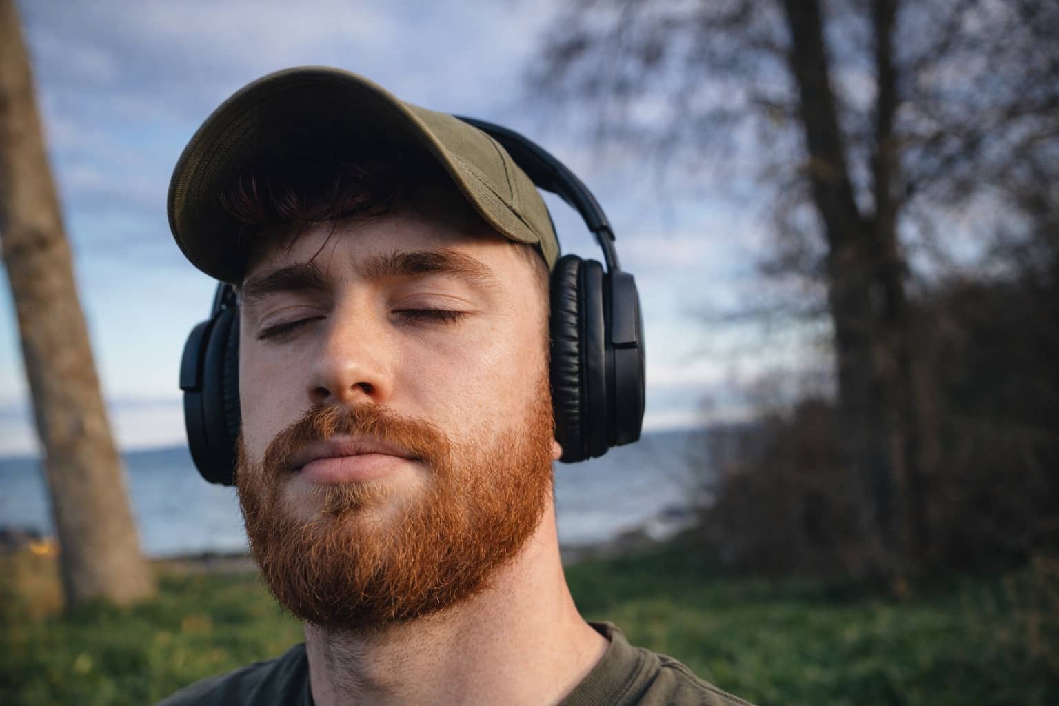 Bearded man with eyes closed wearing headphones outdoors, capturing the vibe of popular tiktok memes.