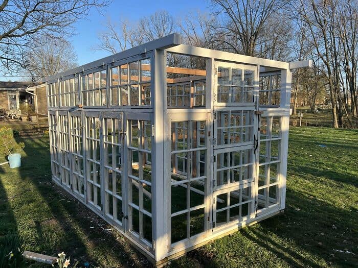 Upcycled backyard greenhouse constructed from vintage glass windows and a timber frame for cool diy woodworking projects.