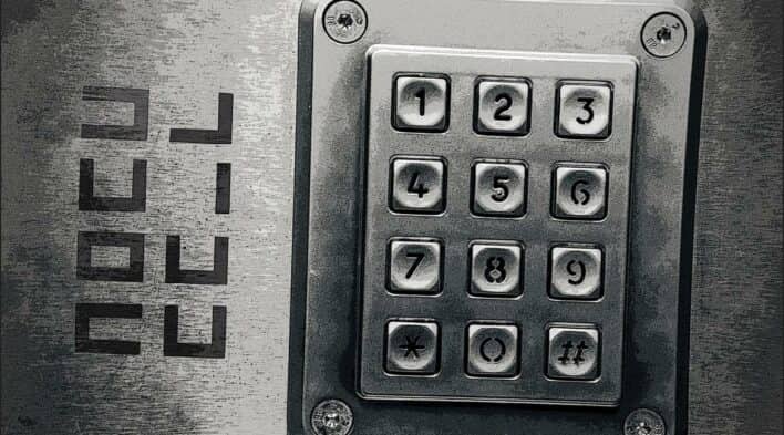 Close-up of a metal keypad with a cryptic four-letter code "OPEN" or "LOCK" etched on the left.