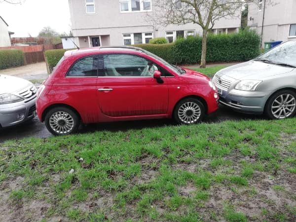 parking fail: A grey sedan parked perpendicularly across the yellow lines of multiple parking spaces in an open lot