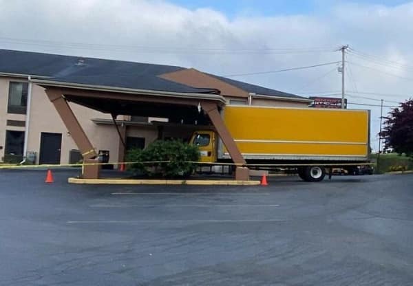 driving fail: A large yellow box truck wedged under a collapsed hotel entrance portico after striking the low-clearance roof