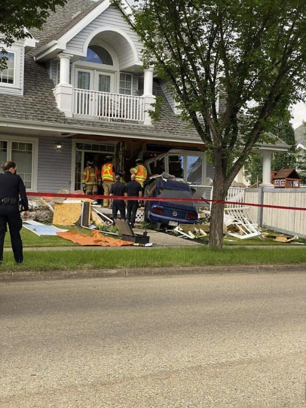 car fail: A blue sedan crashed through the front wall of a suburban house with emergency responders and caution tape at the scene