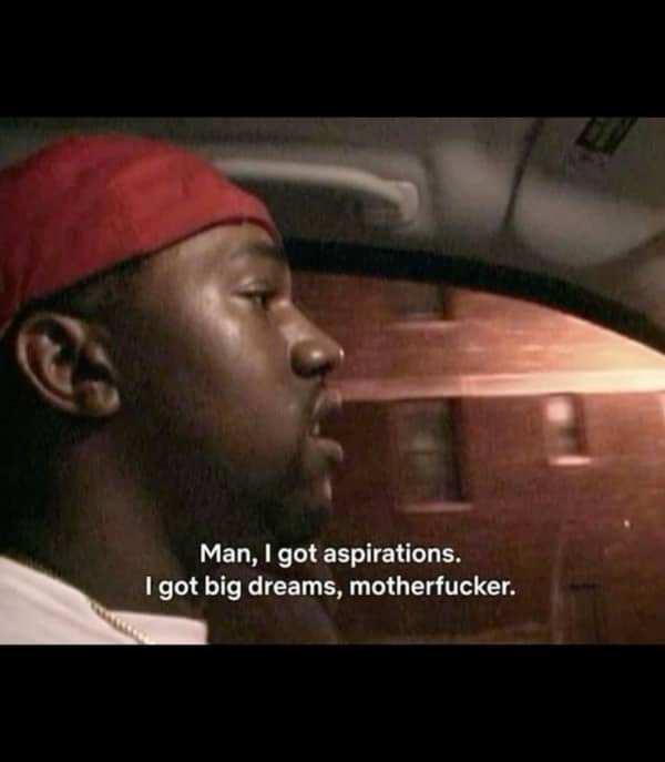 Movie screencap of a man in a car declaring that he has big aspirations and dreams.