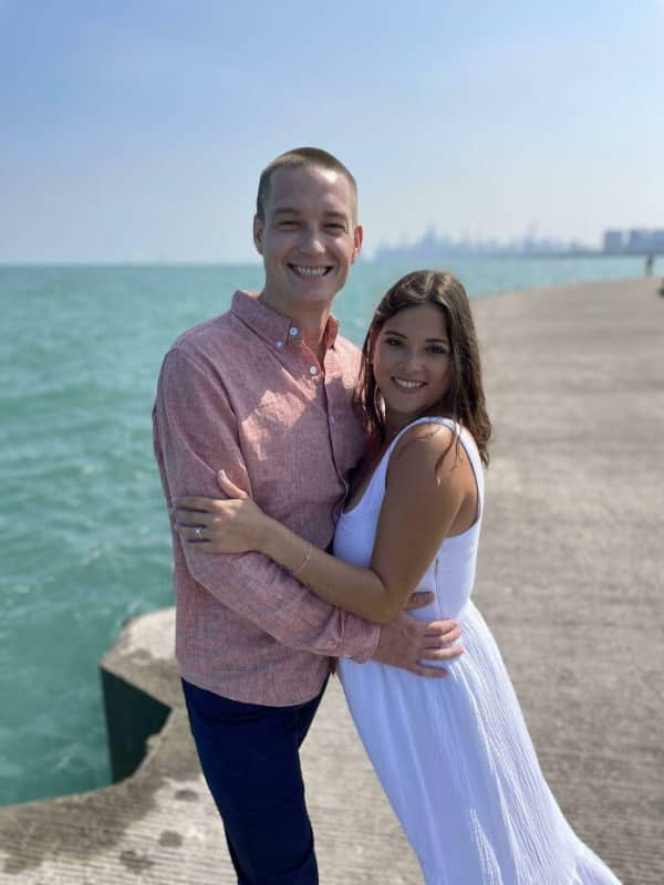 Couple posing by the sea where the man's legs appear to belong to the woman.