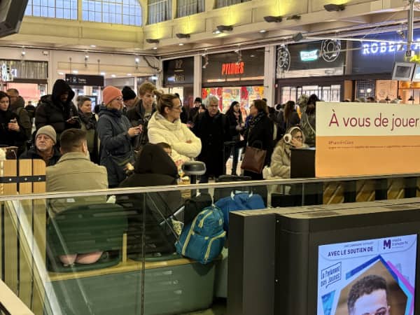 Crowded train station where a woman’s pink leggings create an accidental optical illusion on a bench.