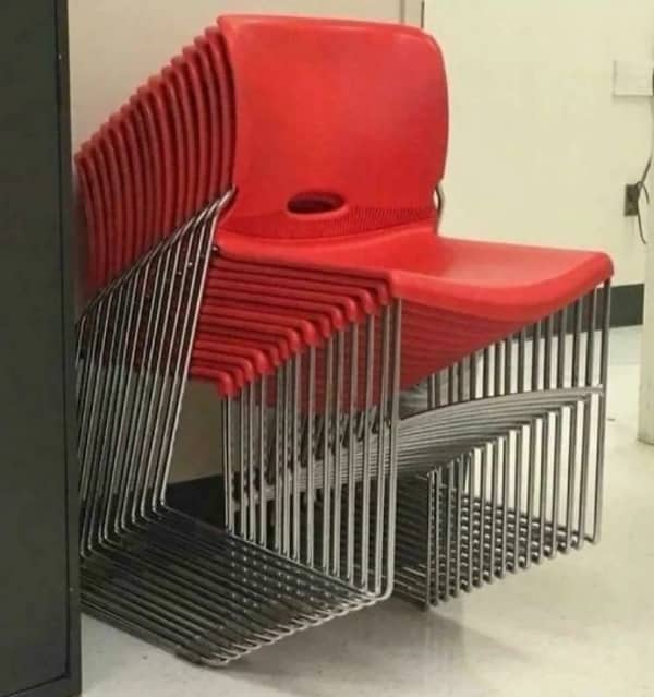 A stack of red plastic chairs creating a dizzying, repetitive visual pattern with their legs.