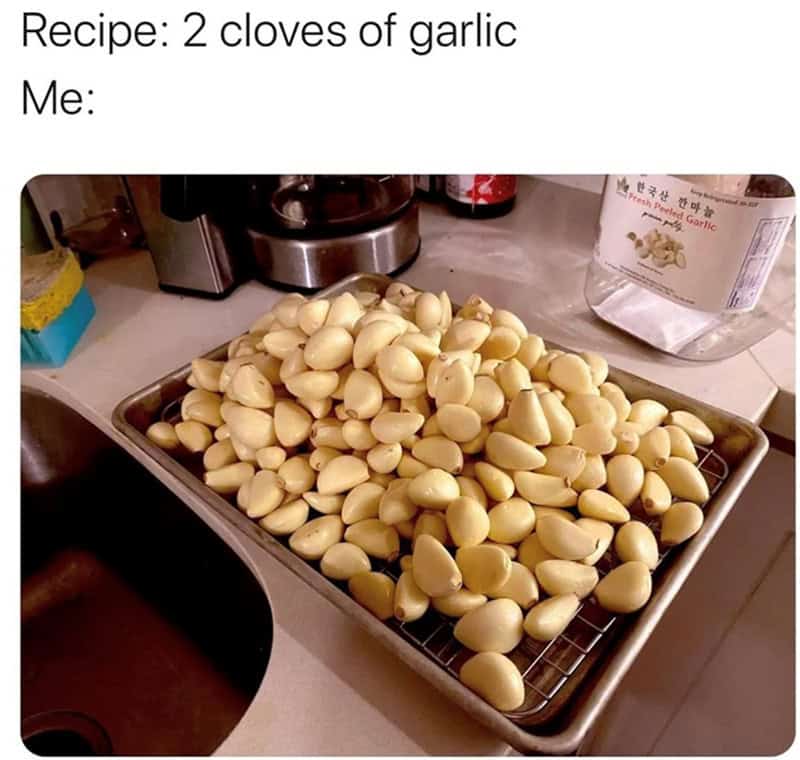 The ultimate garlic lover's cooking memes post, showing a massive industrial baking pan overflowing with hundreds of peeled garlic cloves to perfectly represent the home cook's interpretation of a recipe asking for "2 cloves."