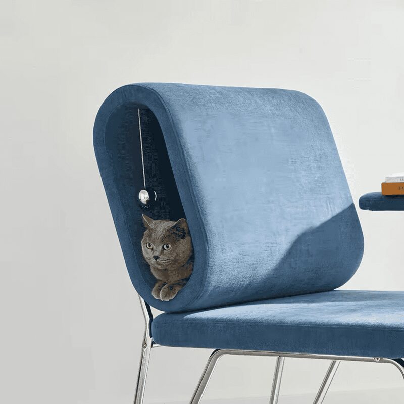 Stylish blue velvet armchair featuring a built-in circular cat tunnel and a gray cat inside.