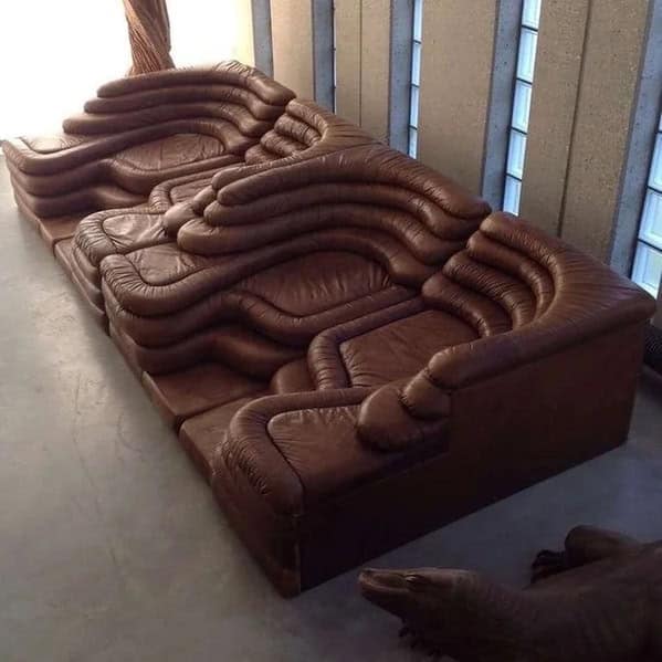 A cursed furniture leather sofa with an excessive amount of lumpy, layered rolls that resemble human flesh or a Shar Pei dog.