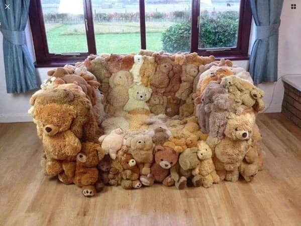 A cursed furniture armchair constructed entirely from dozens of stuffed teddy bears sewn together, creating a lumpy and unsettling seat.