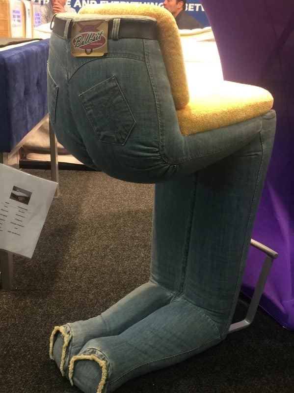 A weird furniture barstool designed to look like a pair of human legs wearing denim jeans, bent at the knees to form a seat labeled "Bull-sit."