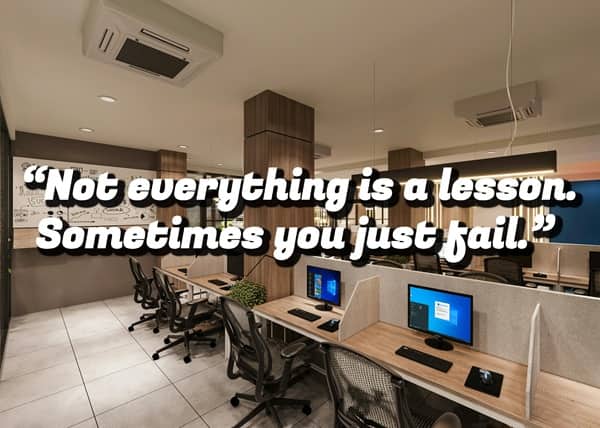 A modern, empty office space with multiple computer stations and a demotivational quote about failing.
