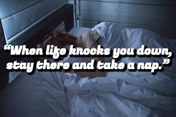 A person lying in bed under white covers with a demotivational quote suggesting taking a nap.