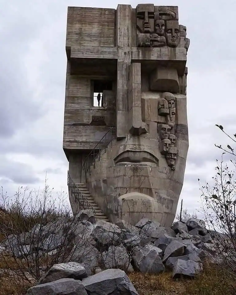 Large concrete monument Mask of Sorrow in Magadan depicting many crying faces in Brutalist style.