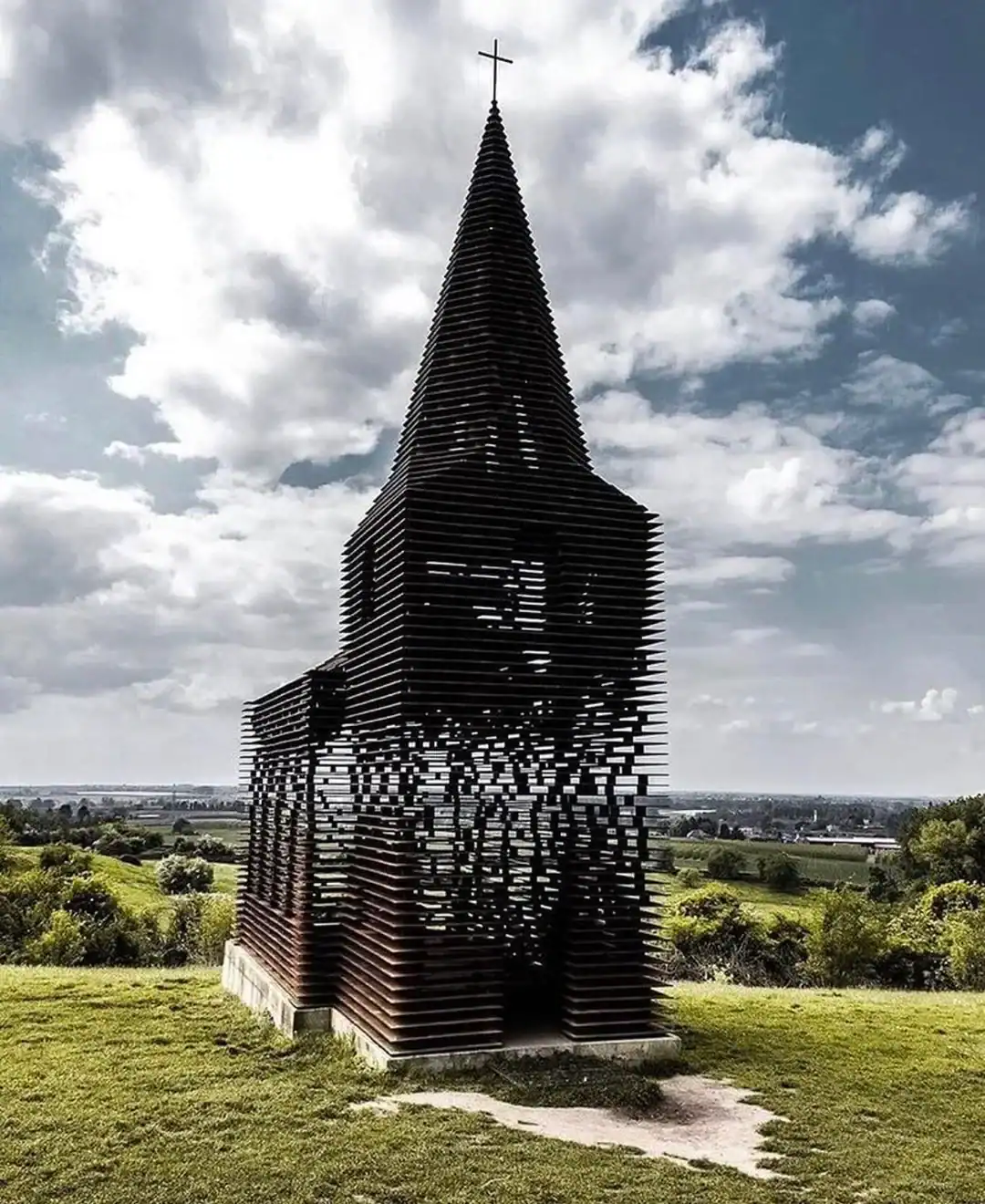 See Through Church art installation in Belgium made of layered steel plates appearing translucent against sky.