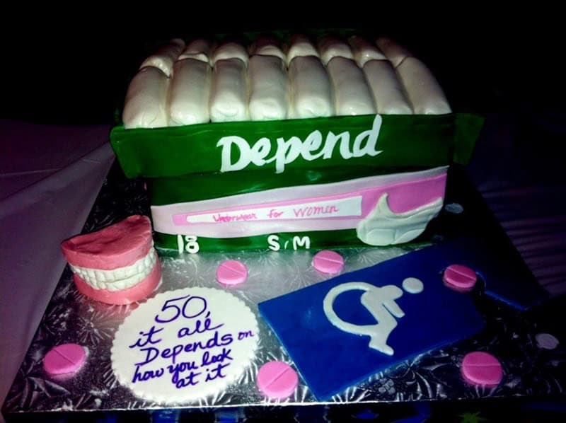 A creative 50th birthday funny cake sculpted to look like a pack of Depend underwear with a side of dentures and pills.