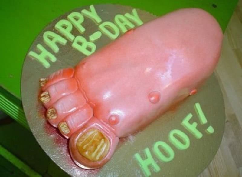 A gross but funny cake sculpted to look like a realistic human foot with the word Hoof written in green icing.