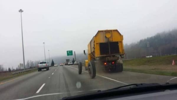 A confusing and hilarious automotive funny fail captured on a misty highway, showing a bizarre yellow farm vehicle that appears to be driving completely backwards down the road.