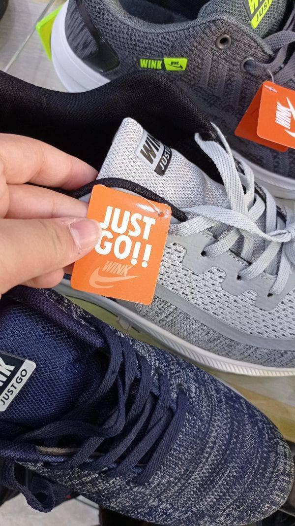 Fake Nike running shoes with a swoosh logo that reads Wink Just Go. Hilarious bootleg sneakers found while shopping.