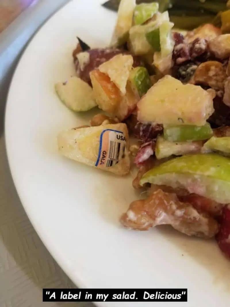 Funny fail photo of a Gala apple sticker found mixed into a fruit salad during a meal.
