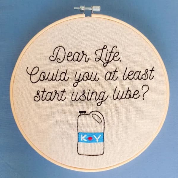 Embroidery art in a hoop reading Dear Life could you at least start using lube.