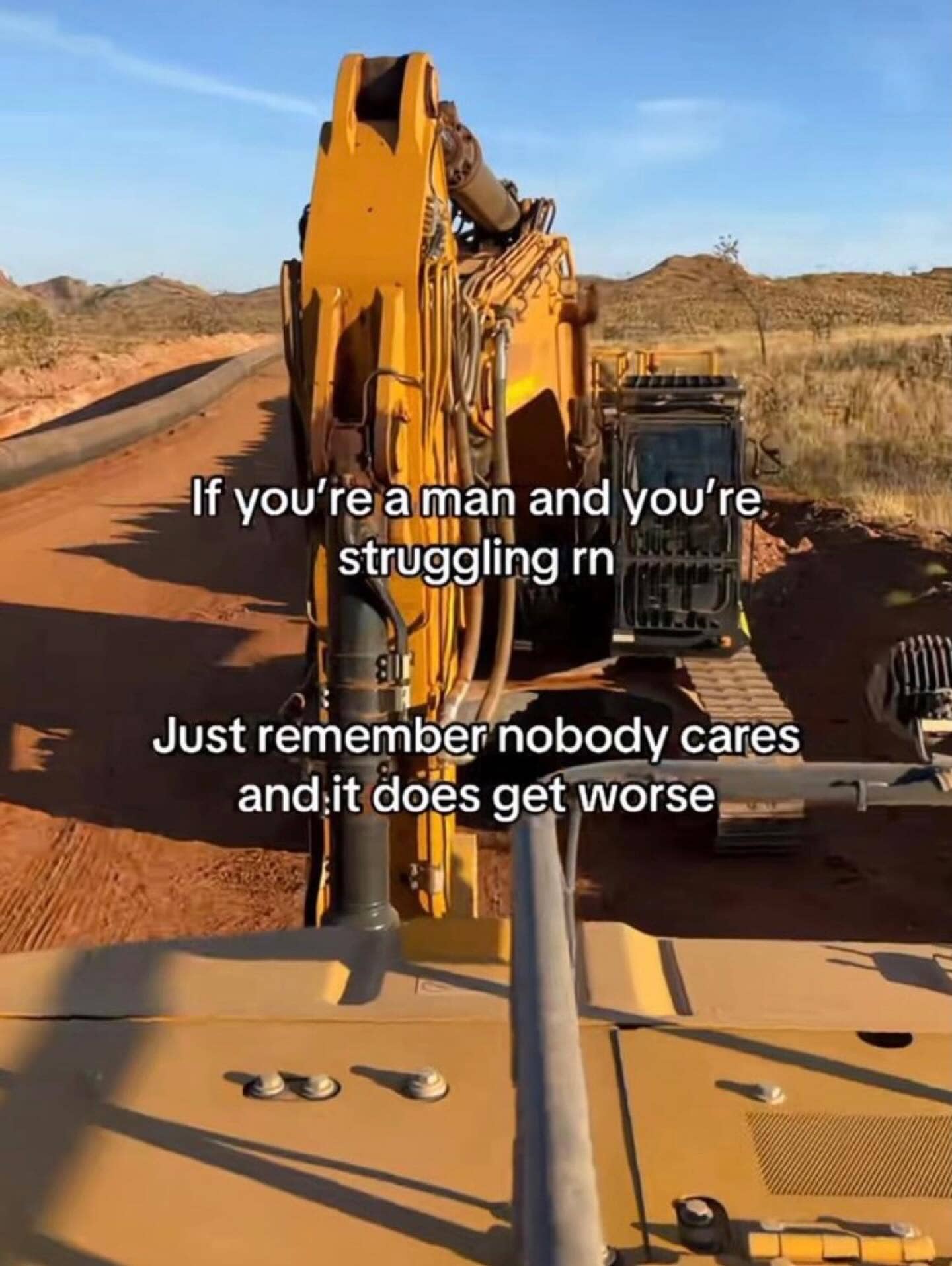 Inspirational-style meme over construction equipment with a dark humor message about men's struggles getting worse.