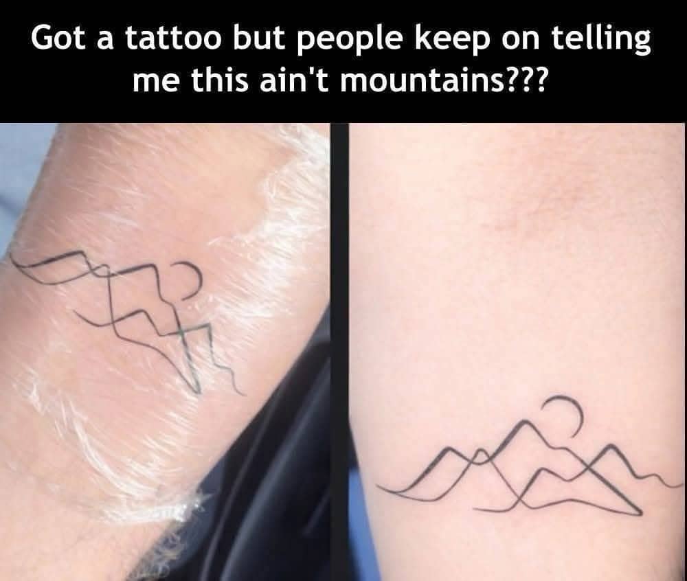 Minimalist mountain line tattoo on a forearm with a sun that resembles an unintended suggestive shape.