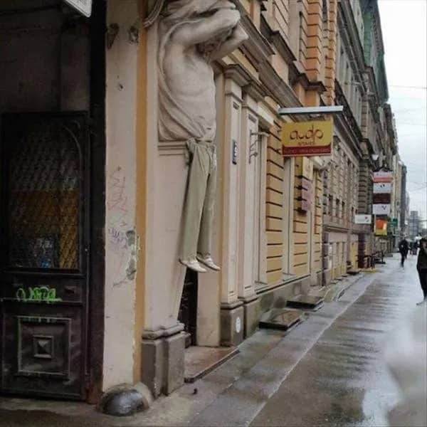 Architectural building statue of a man wearing actual tan trousers and white shoes as a prank.