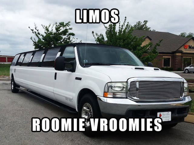 A long white stretch limousine parked in a lot with the text "Roomie Vroomies."