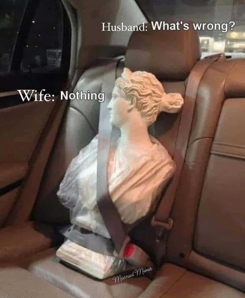 A hilarious marriage meme featuring a classical statue bust buckled into a car seat, looking away dramatically to represent a wife giving the "silent treatment" when she says "Nothing" is wrong.
