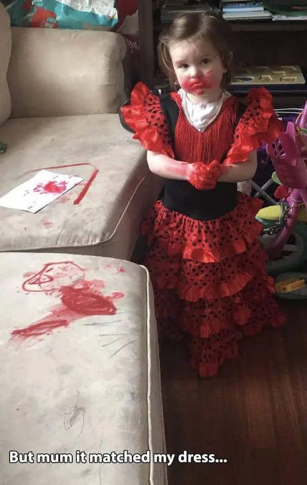 A classic parenting funny meme found in a meme dump showing a guilty toddler standing next to a completely ruined white couch covered in red scribbles, wearing a red flamenco dress with red marker all over her hands and face with the hilarious excuse, "But mum it matched my dress...".