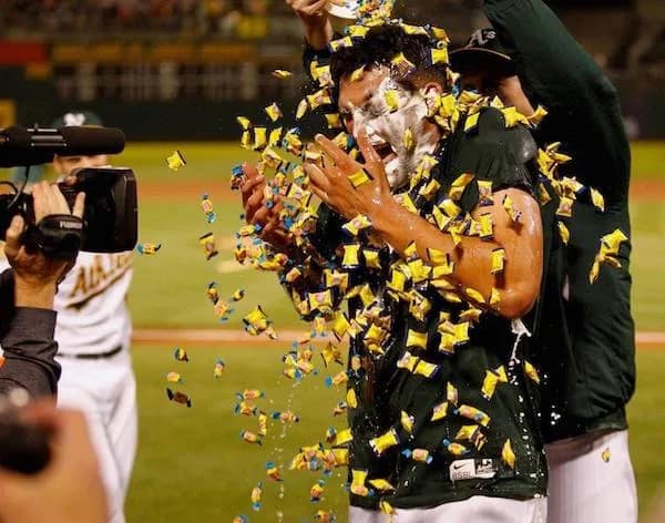 A high-energy meme dump photo of a baseball player being violently showered with hundreds of pieces of gum or candy during a post-game celebration.