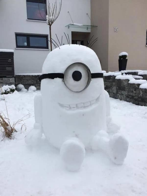 A cursed winter funny memes creation showing a snowman sculpted perfectly into the shape of a Minion, sitting ominously on a snowy lawn.