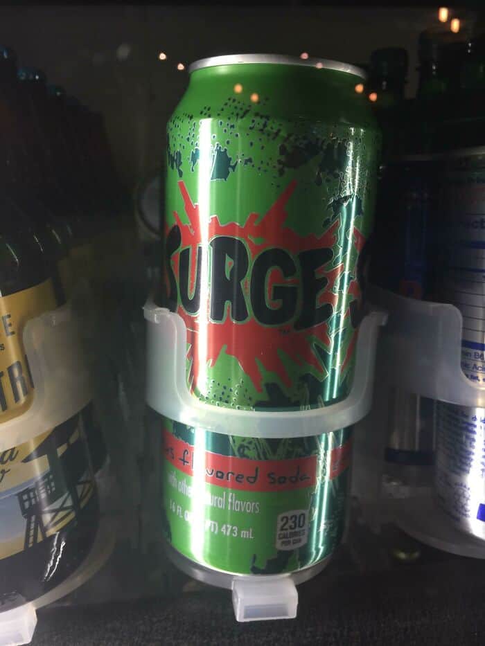 A can of Surge soda sitting in a cooler, a high-caffeine nostalgic drink that defined the extreme "citrus soda wars" of the 1990s.