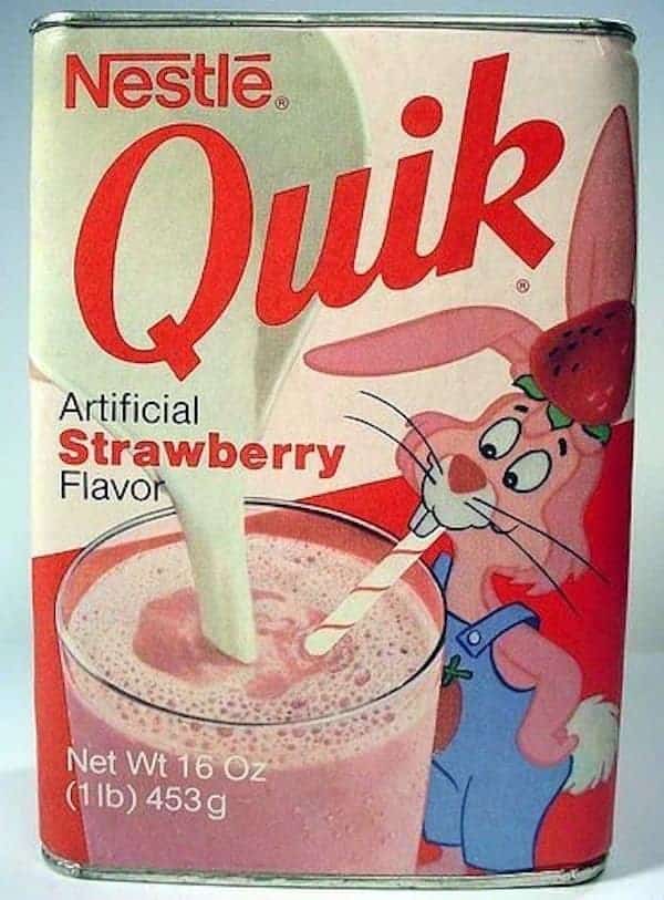 A metal tin of Nestlé Quik Strawberry powder, a beloved nostalgic drink mix featuring the iconic bunny mascot mixing a glass of pink milk.