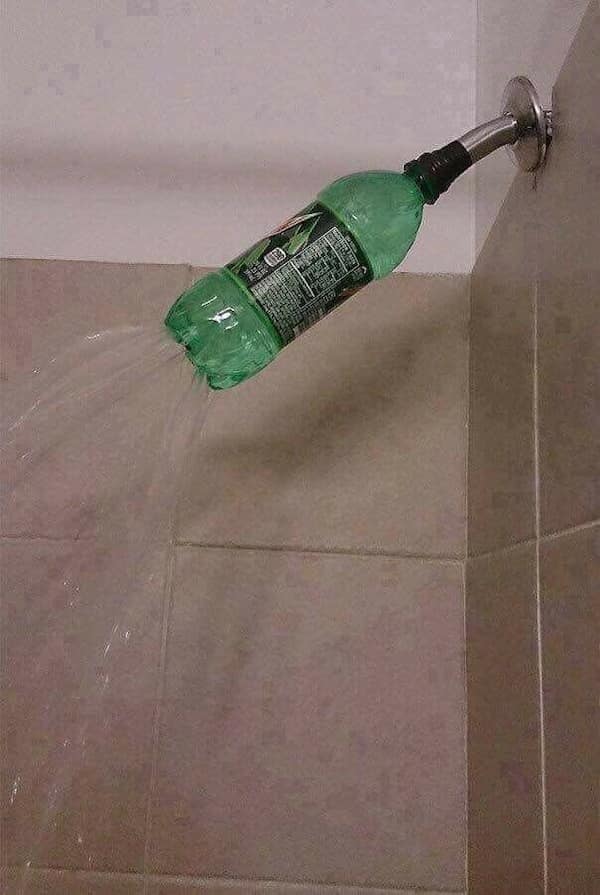 A redneck DIY shower head made from a green plastic soda bottle taped to the water pipe with holes poked in the bottom