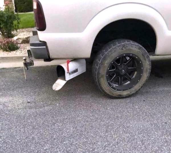 A redneck ingenuity modification on a white truck where the exhaust pipe tip has been replaced with a standard white mailbox.
