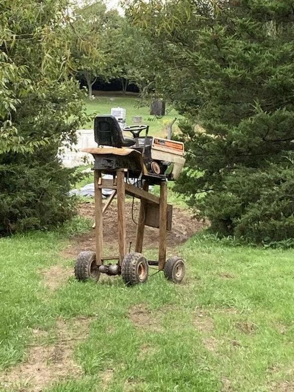 A redneck DIY "high-clearance" lawn mower built on tall wooden legs to ride above the ground.