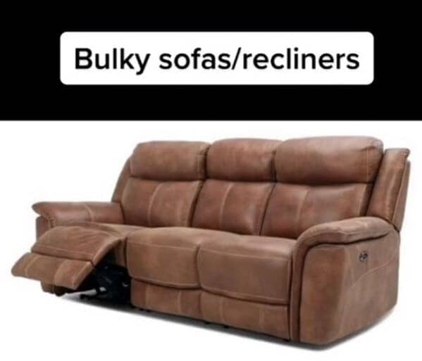A large, oversized brown leather reclining sofa with heavy cushions and visible mechanical parts.